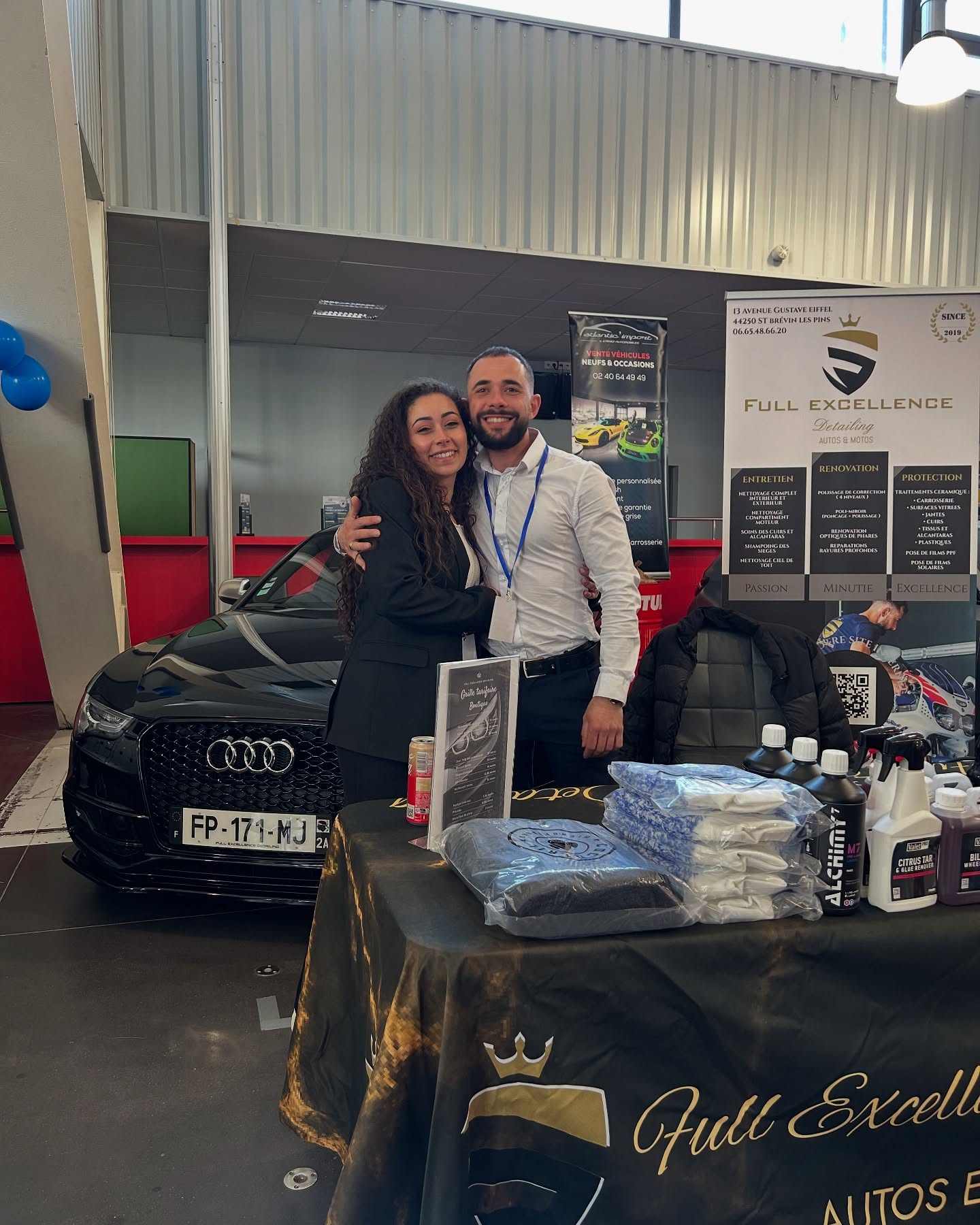 Florian Trebaol Rocca et l'équipe Full Excellence Detailing sur le stand de l'atelier lors d'un salon automobile, devant une Audi noire